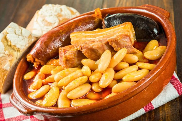 Una cazuelita de barro con una porción de fabada asturiana con tocino, chorizo y morcilla.
