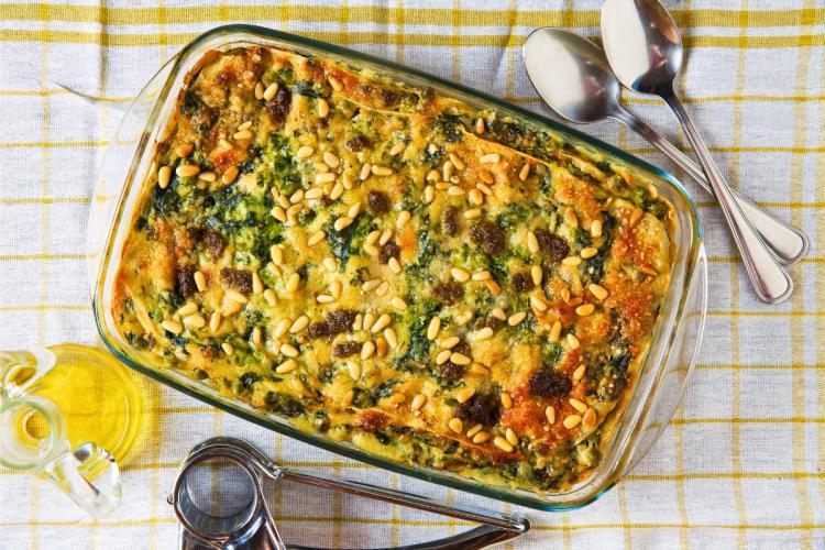 Una fuente de lasaña de espinacas y queso recién salida del horno.