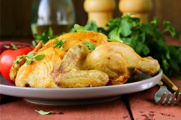 Un pollo entero asado con hierbas, vista lateral.