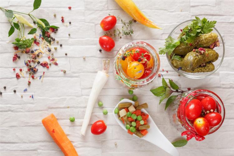 Una selección de verduras encurtidas con las especias usadas al fondo.