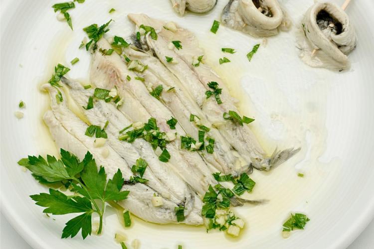 Boquerones en vinagre con aceite de oliva, ajo y perejil picados.