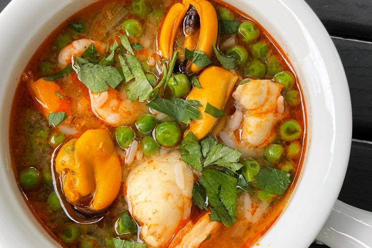 Un cacillo de loza con sopa de pescado y marisco.