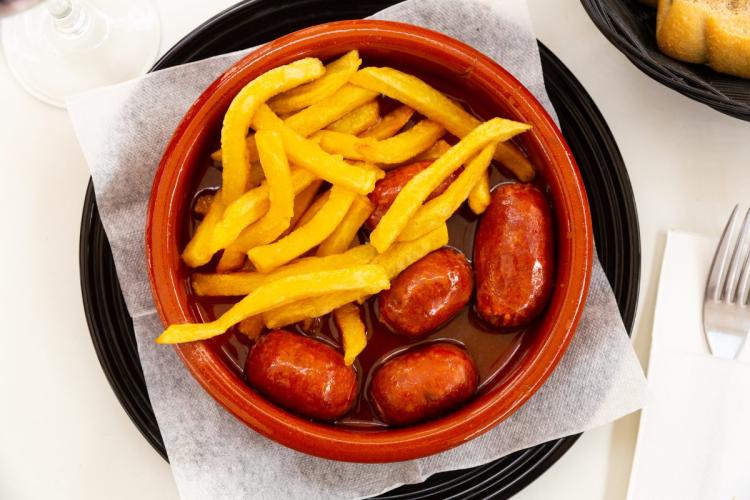 Cazuelita de barro con chorizo a la sidra acompañado de patatas fritas.
