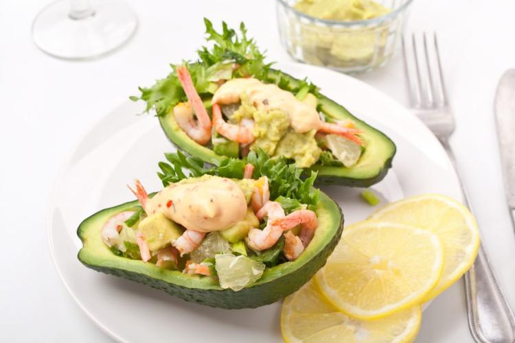Ensalada de marisco y aguacate con la ensalada rellenanco el hueco vaciado en el aguacate.
