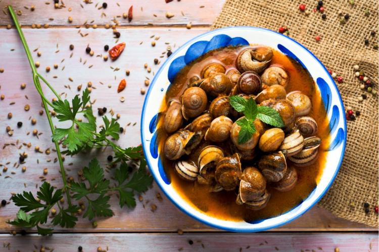 Una cazuela con caaracoles en salsa picante.