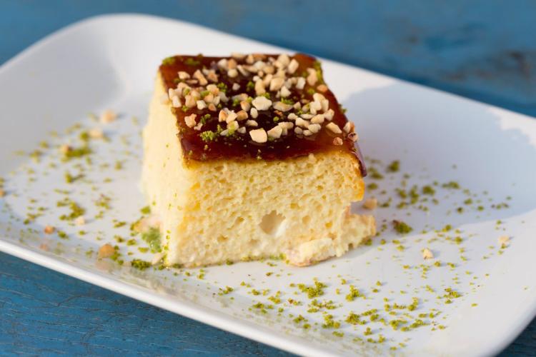 Un trozo de pastel de tres leches decorado con pistacho picado.