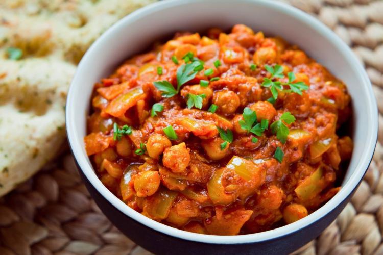 Un recipiente con chana masala decorado con cilantro fresco.