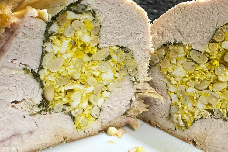 Sección de una pechuga de pavo rellena con huevo duro picado y piñones.