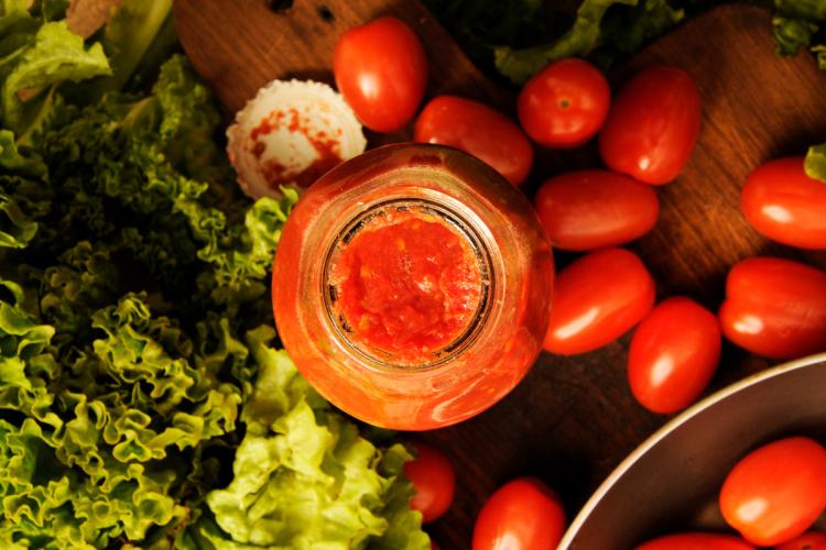 Salsa pummarola en recipiente de cristal rodeada de los ingredientes frescos.