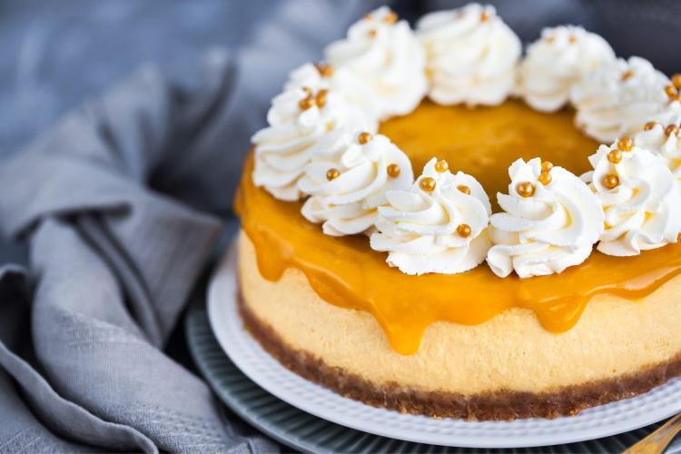 Tarta de queso y mango decorada con rosetas de nata montada.