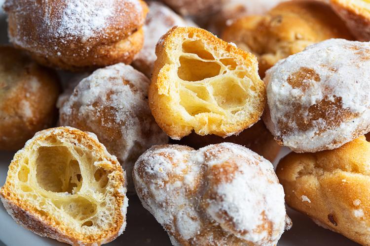 Buñuelos de viento recién hechos, uno abierto mostrando el interior esponjoso.