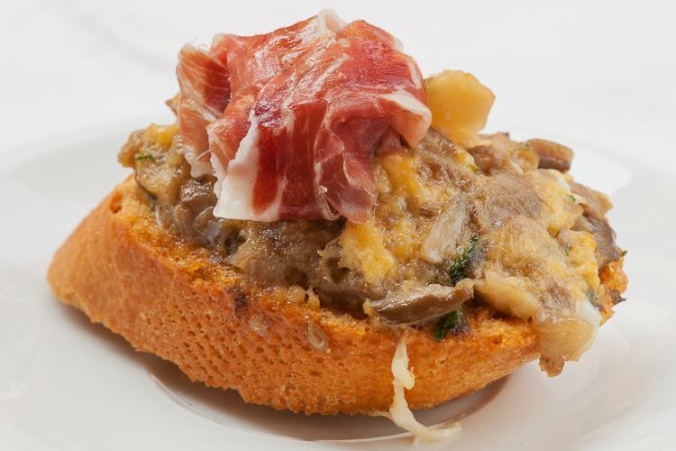 Pincho de revuelto de setas decorado con una loncha de jamón serrano.