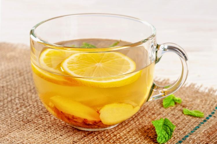 Una taza con una infusión de jengibre y limón, decorada con hojas de hierbabuena.