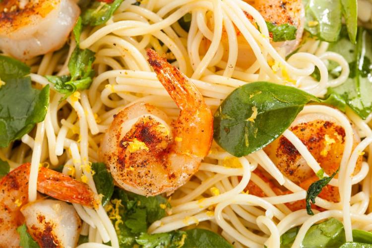 Pasta con gambas y limón casera, decorada con hojas de albahaca.