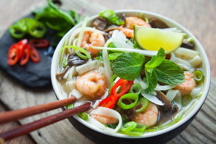 Un cuenco con sopa pho de gambas y setas.