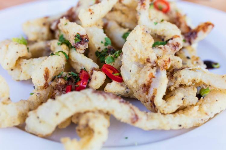 Calamares fritos con sal y pimenta de limón con cilantro fresco y chile tailandés.