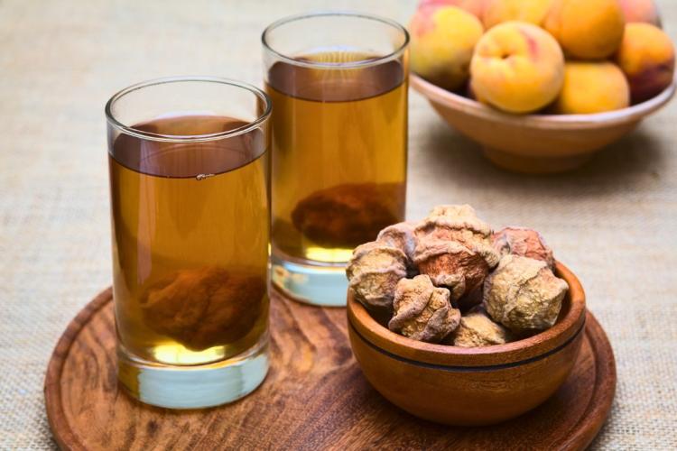 Dos vasos de moccchinchi, una bebida heca con duraznos secos, junto con un plato de duraznos secos.