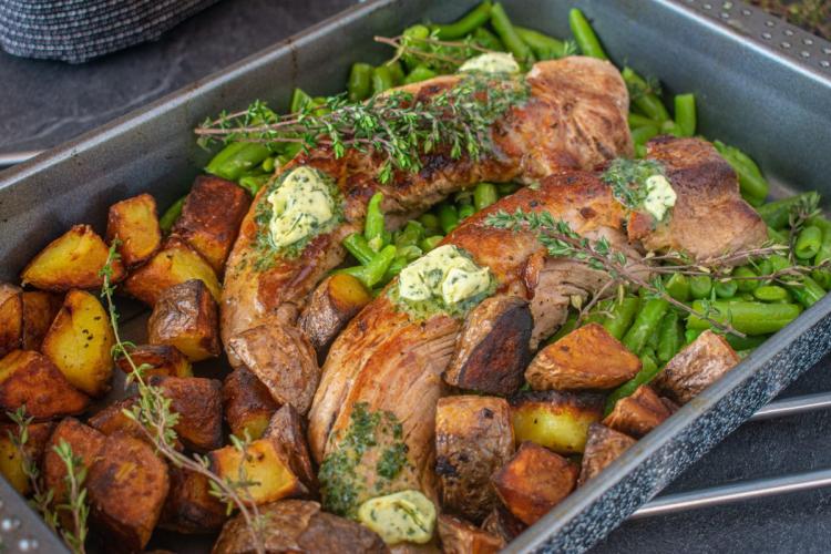 Una fuente de horno con solomillo de cerdo asado con patatas y judías verdes.