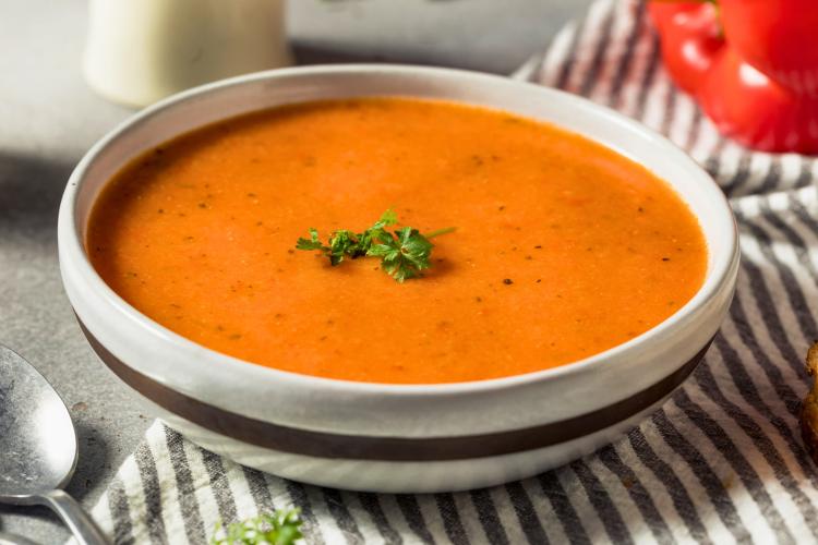 Un plato hondo con sopa de pimientos morrones.