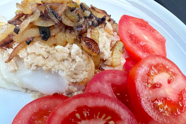 Pescado al horno con tahini y rodajas de tomate.