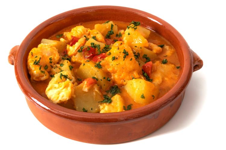 Patatas guisadas con bacalao en una cazuela de barro.