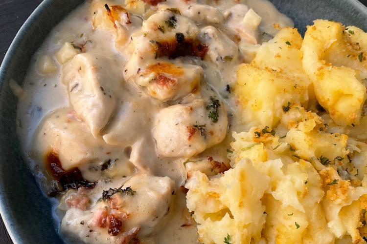 Un plato de pollo a la bretona con jamón desmenuzado acompañado con puré de patata al queso.