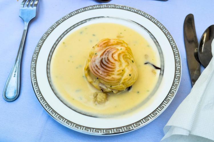 Repollo relleno de pescado decorado con puré de patata y acompañado con besamel.