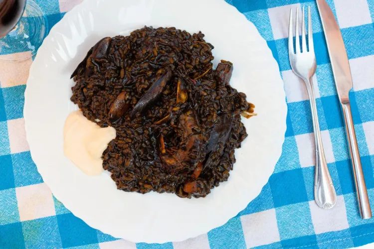 Un plato de arroz negro acompañado con alioli.