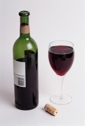 Una botellad de vino tino y una copa con vino tinto.