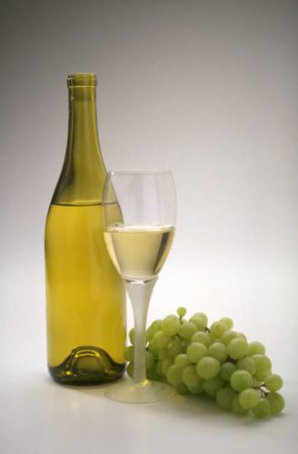 Una botella de vino blanco y uvas.
