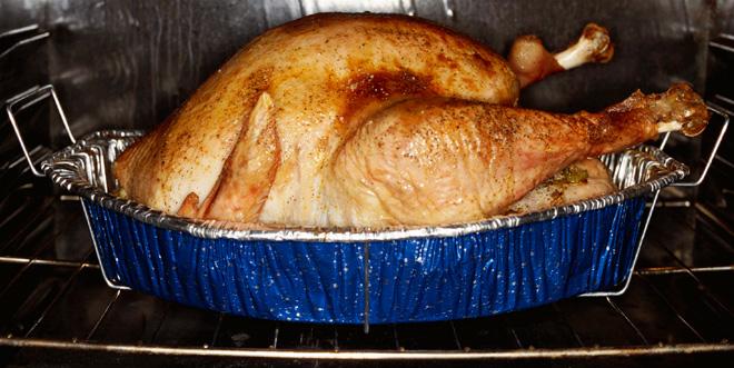 Un pavo asado en una fuente dentro del horno.