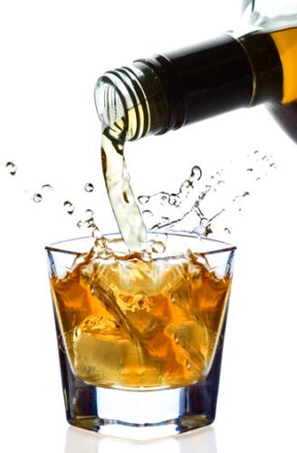 Whisky cayendo en un vaso con hielo.