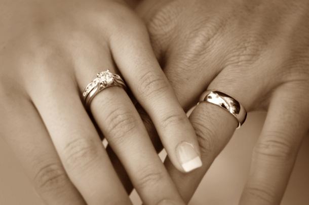 Dos manos cogidas llevando anillos de matrimonio.