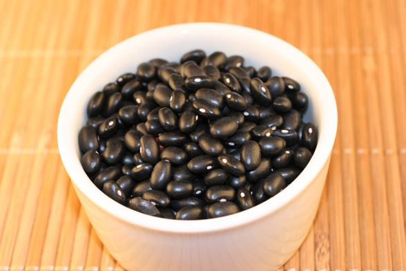 Frijoles negros en un cuenco de loza blanca.