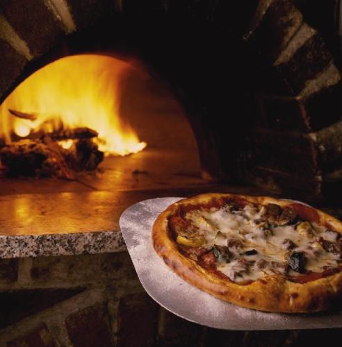 Horno con leña ardiendo y pizza recién hecha.