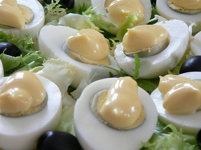 Huevos rellenos cubiertos con mayonesa.