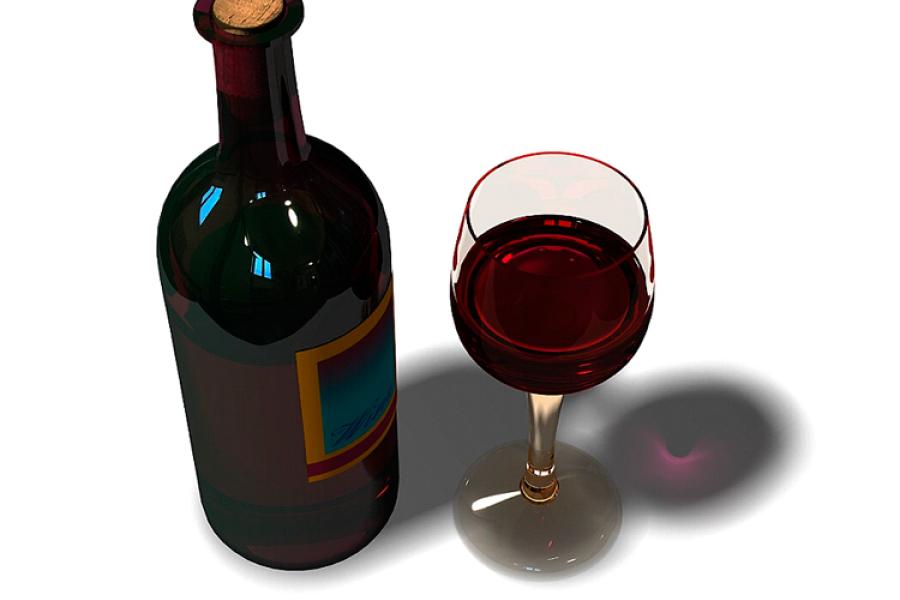 Una botella y una copa de vino tinto.