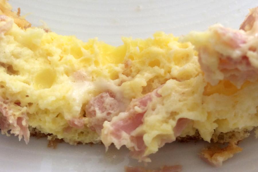 Corte de una tortilla esponjosa de jamón y queso.