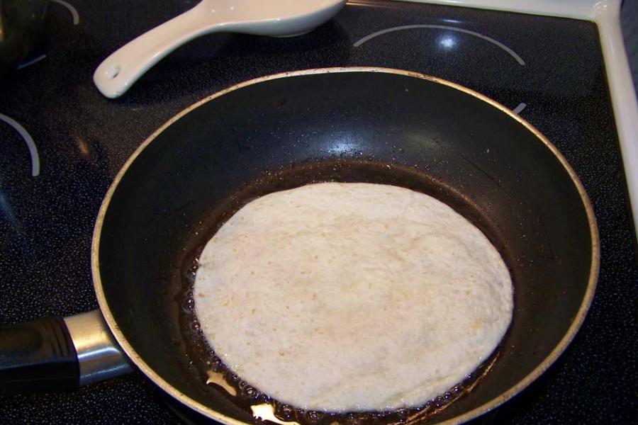 Una tortilla de masa friéndose en una sartén antiadherente.
