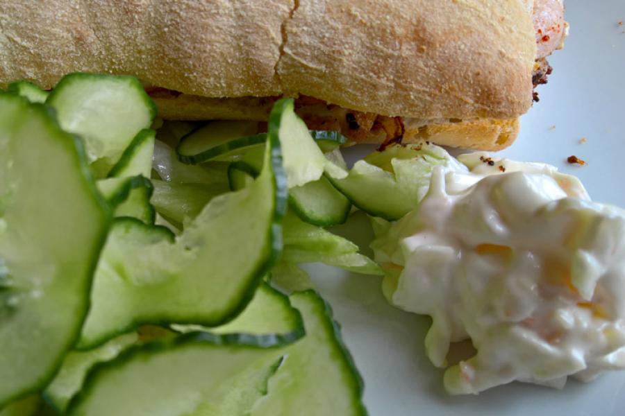 Bocadillo de pollo y tocino con rodajas de pepino y coleslaw.