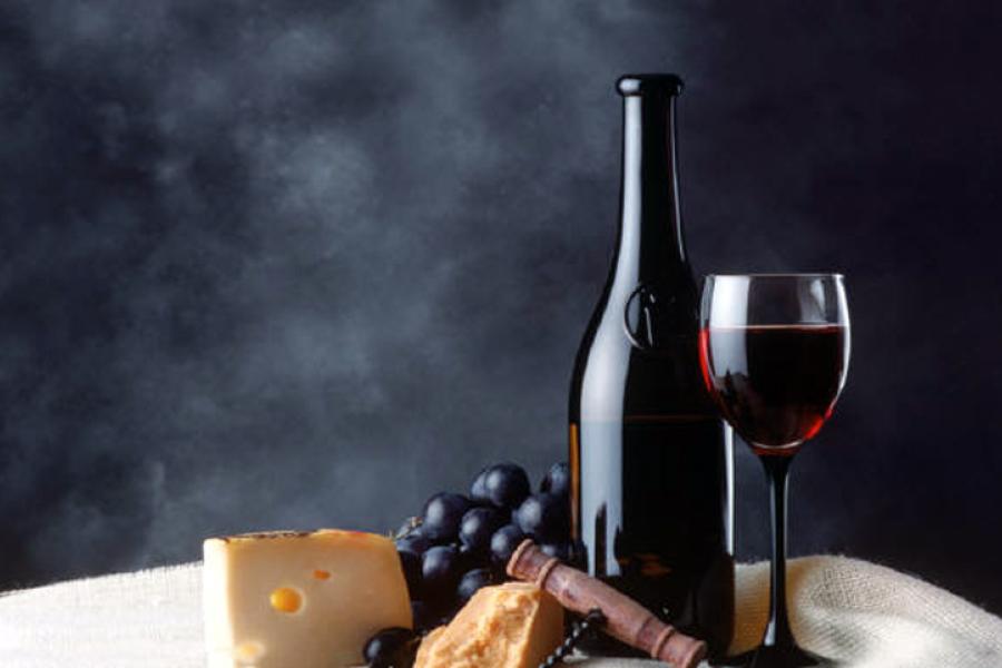 Botella, copa de vino tinto, uvas y queso.