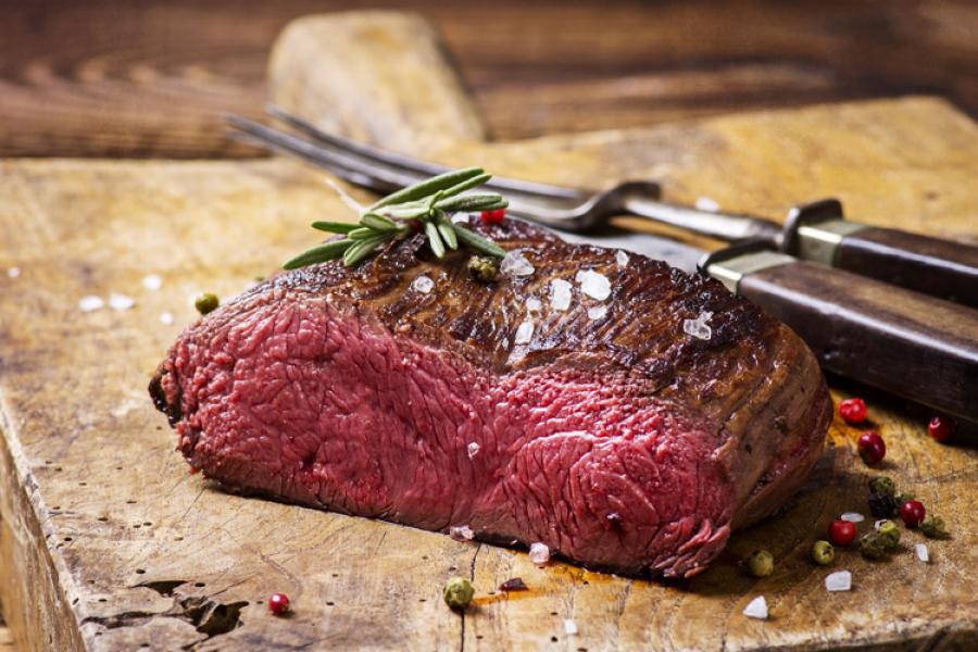 Carne de venado asada sobre tabla de madera.