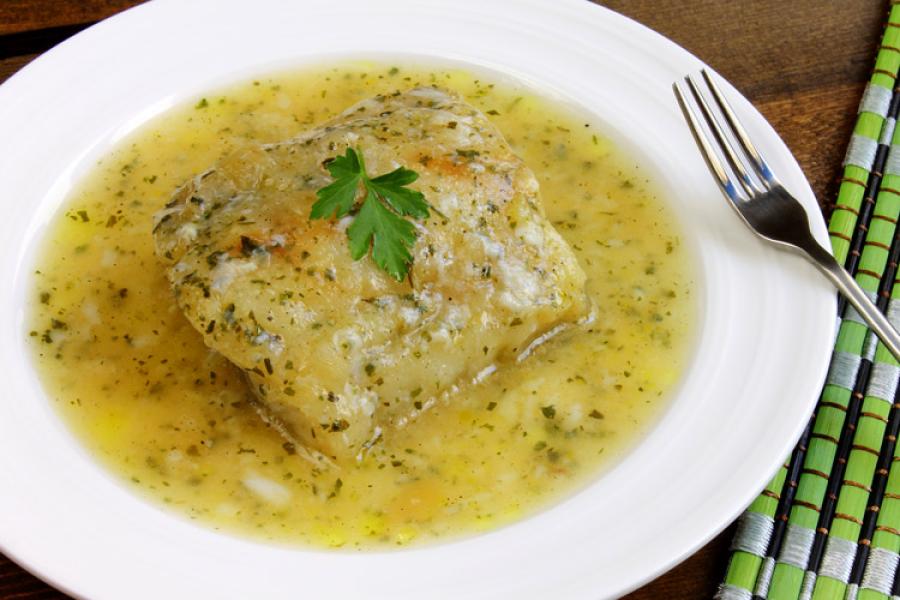 Bacalao en salsa verde servido en un plato de loza.