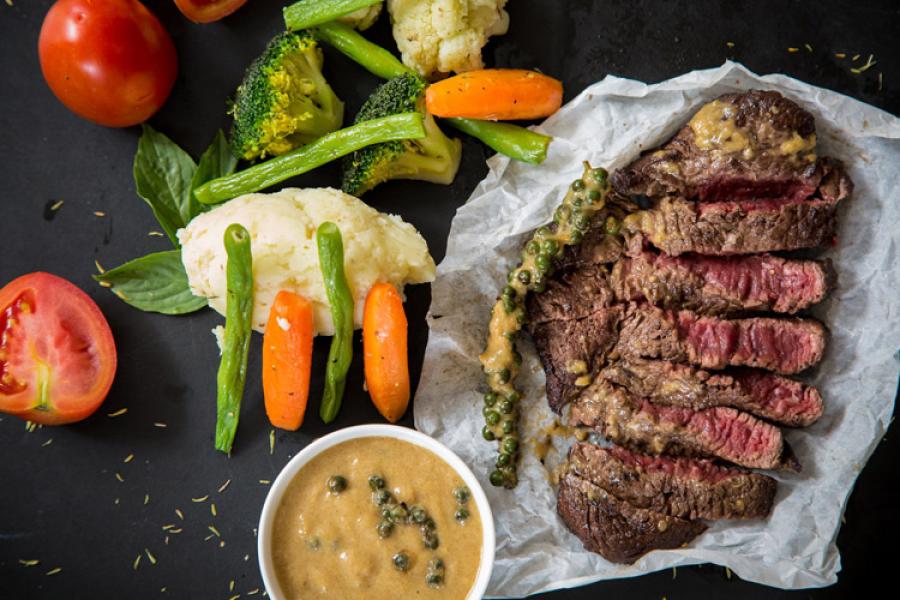 London broil con salsa a la pimienta verde y verduras crudas.