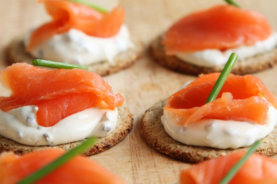 Canapés de salmón ahumado y queso cremoso adornados con cebollino.