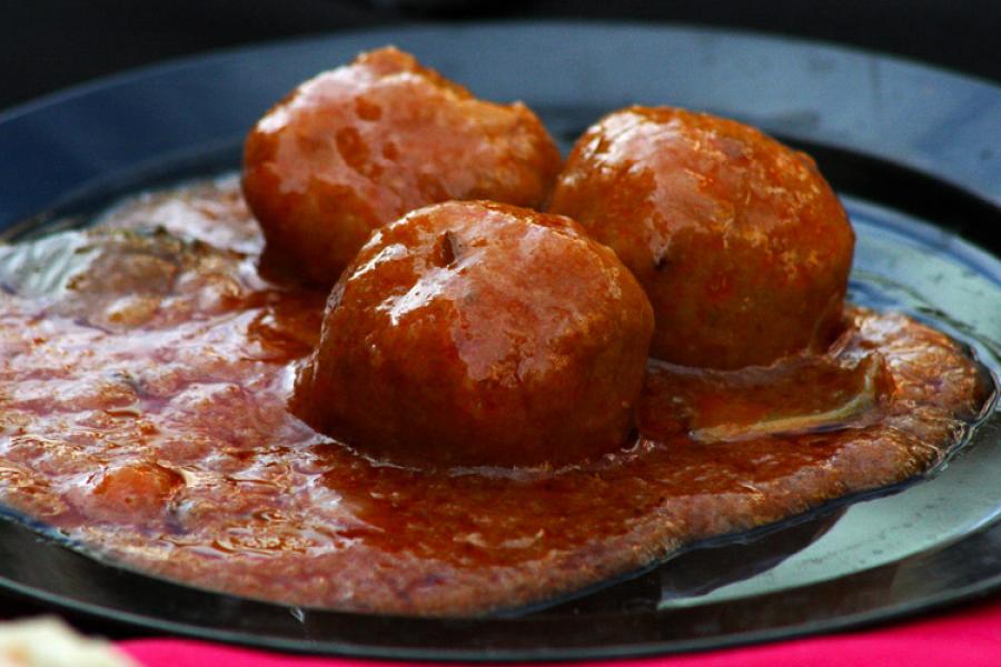 Albóndigas grandes con salsa de tomate en un plato negro.
