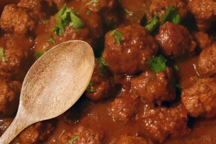 Albóndigas con salsa de tomate y una cuchara de palo.