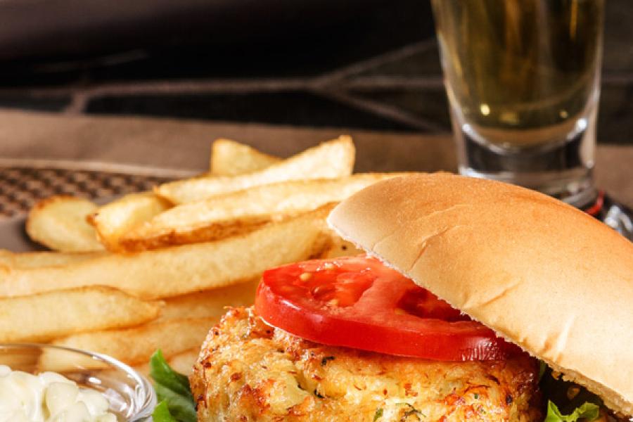 Bocadillo de pastel de cangrejo con patatas fritas y salsa tártara.