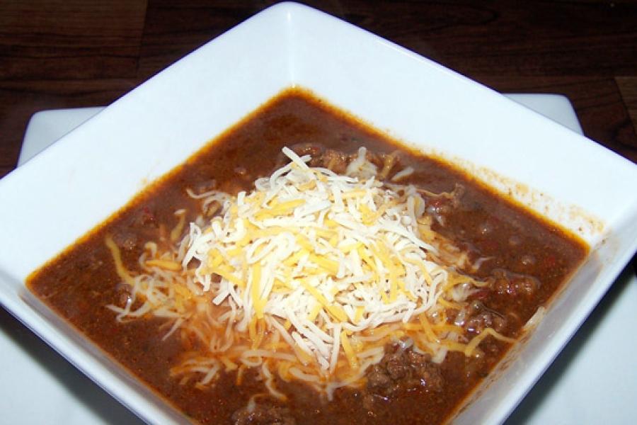Chile con carne y mole en su plato con queso rallado por encima.