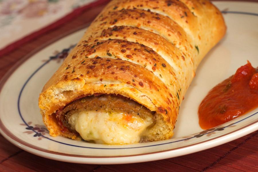 Rollito de salchicón con salsa servido en un plato blanco.